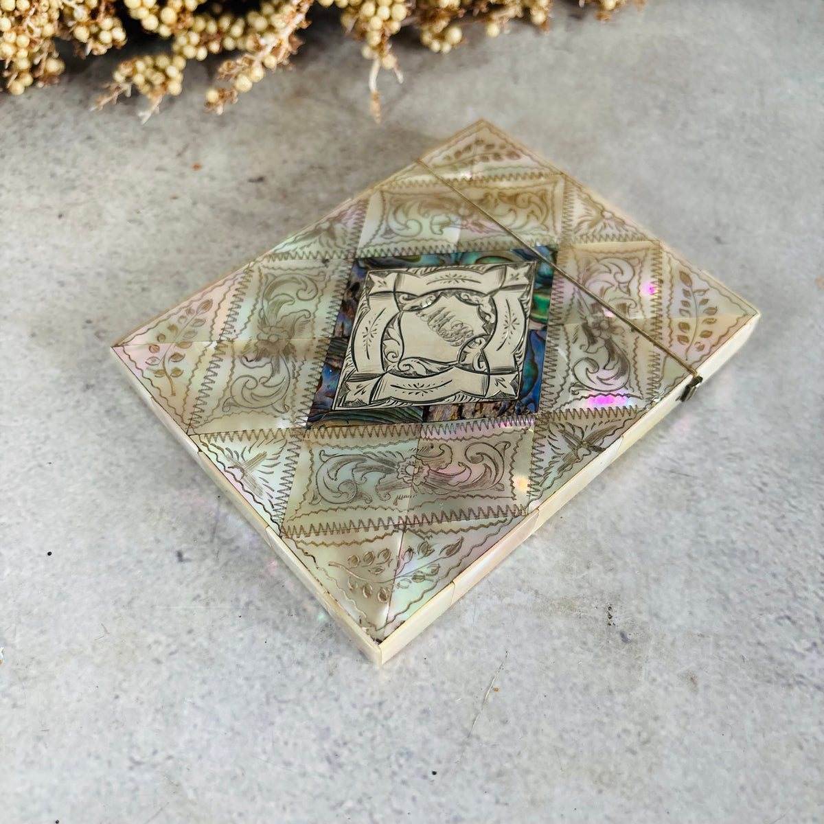 Rare Antique Mother Of Pearl And Sterling Silver Calling Card Case , displayed on a textured gray surface with dried flowers in the background.