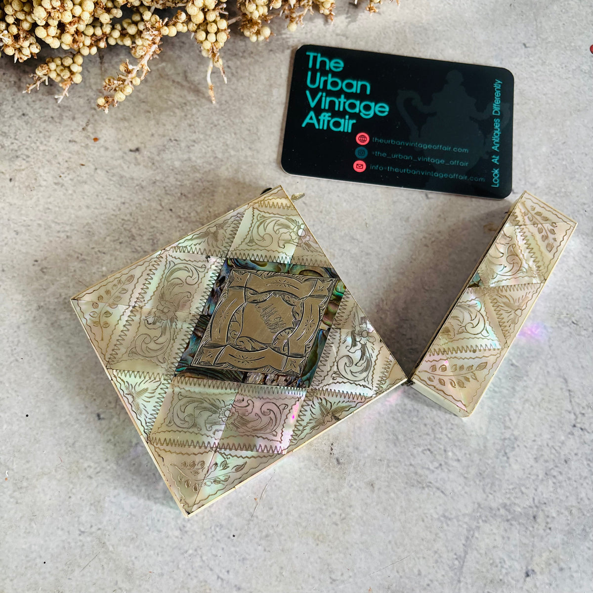 An ornate Rare Antique Mother Of Pearl And Sterling Silver Calling Card Case , shown open on a light textured surface next to a black business card for 'The Urban Vintage Affair'.