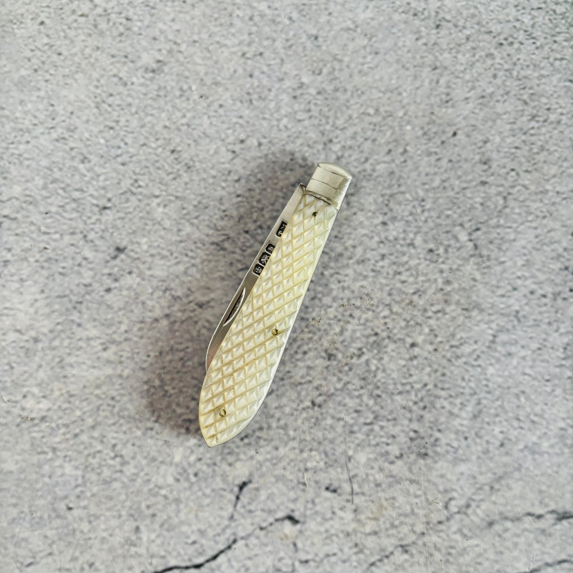Silver pocket knife with textured handle on a gray surface