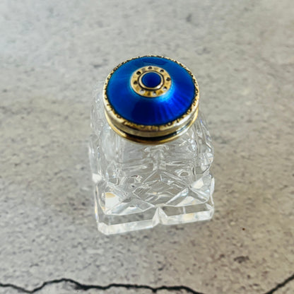 Glass and silver guilloche enamel salt and pepper bottle with colourful stopper on a grey surface