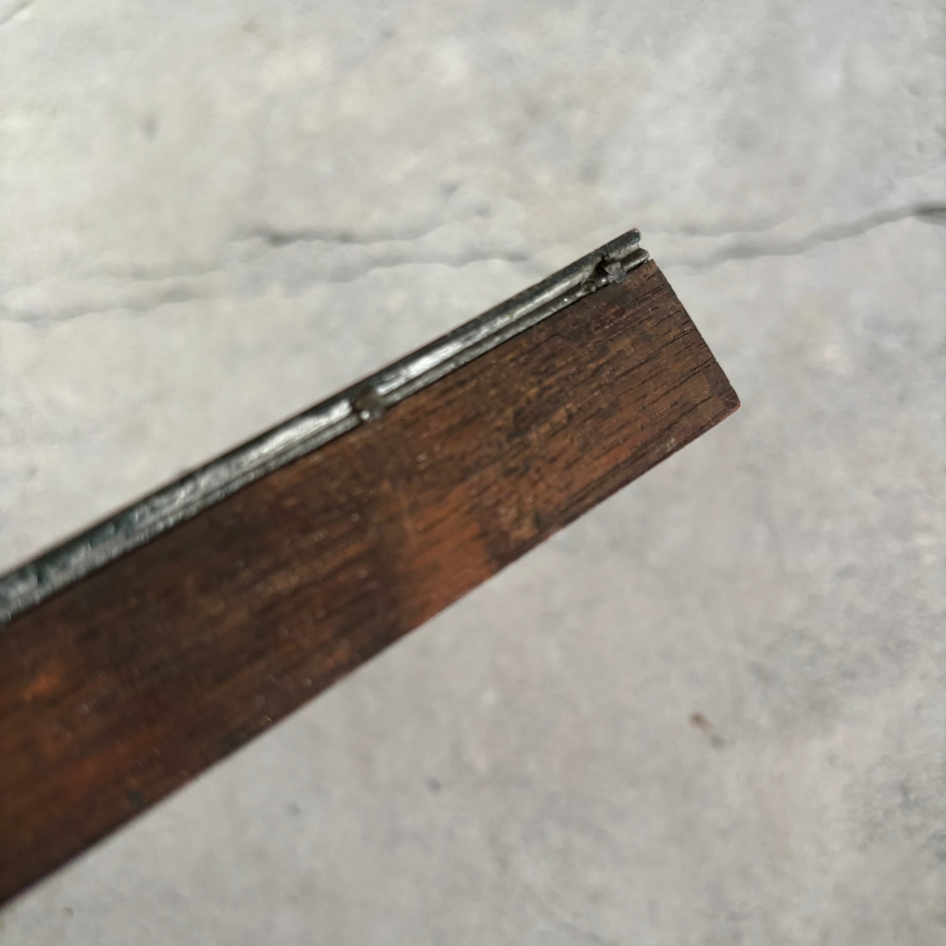 Close-up of a wooden object with metal edge on a marble surface