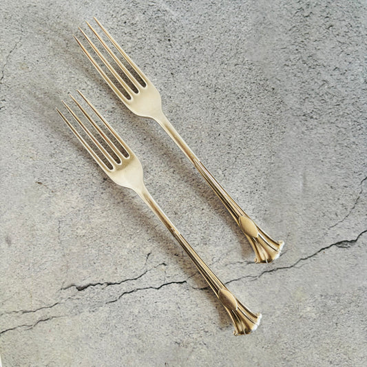 Two silver forks on a textured gray surface