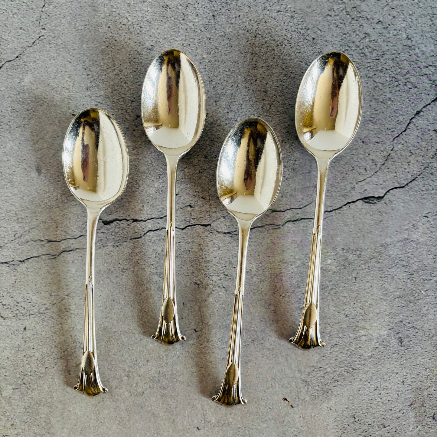 Four silver spoons on a textured grey surface