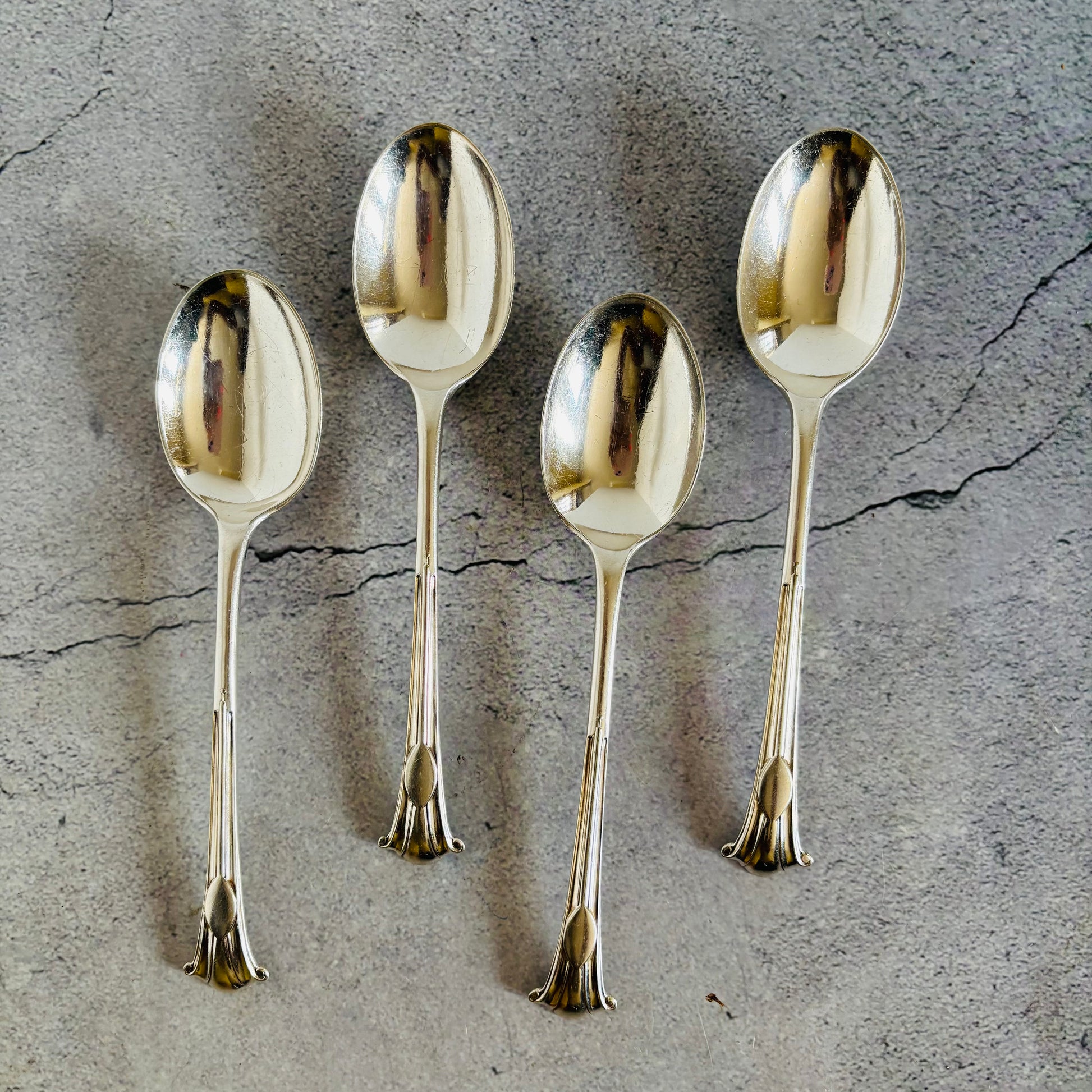 Four silver spoons on a textured grey surface