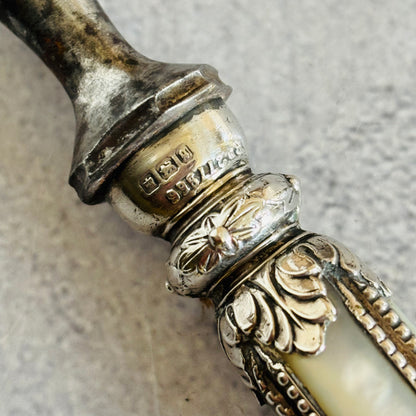 Decorative silver and bone handle with hallmarks engraving on a textured grey background