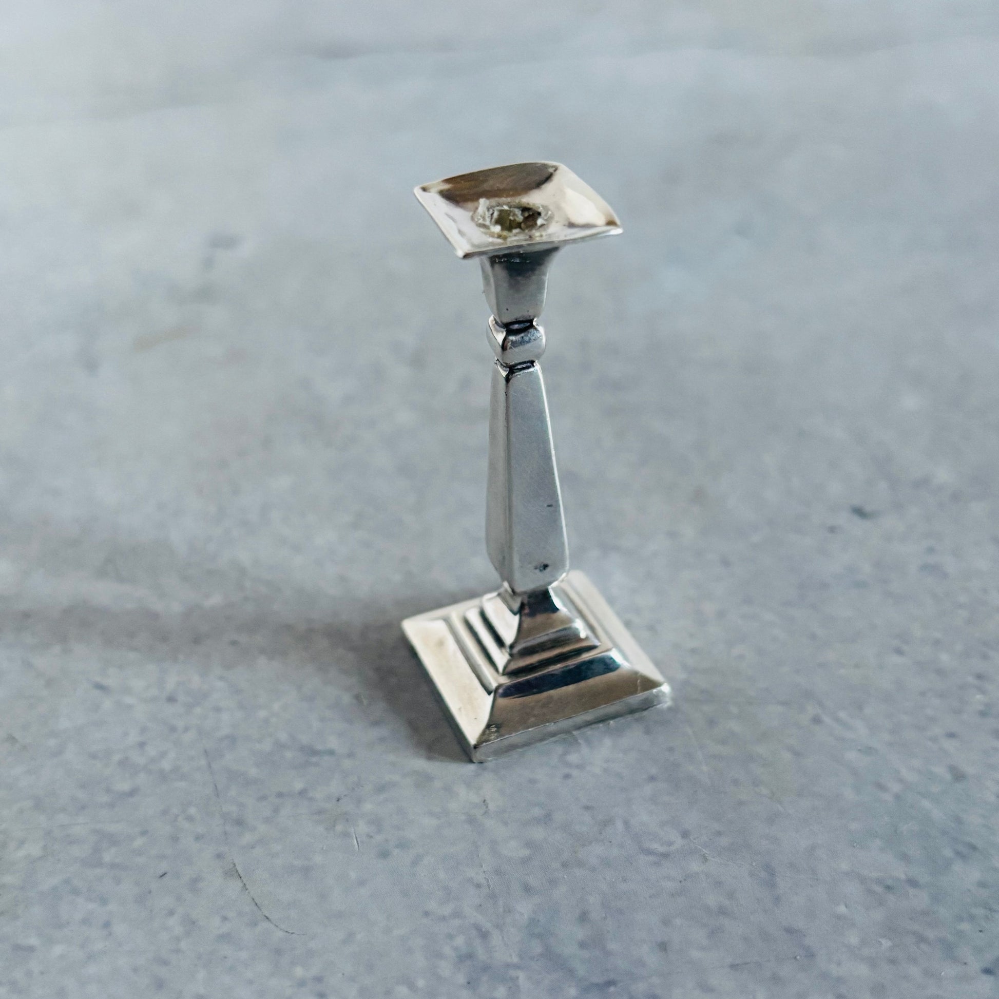 Antique Silver Miniature candle holder on a grey surface