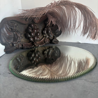 Decorative wooden fragment, feathers, and a Antique Oval Sorcerers Mirror Mat 