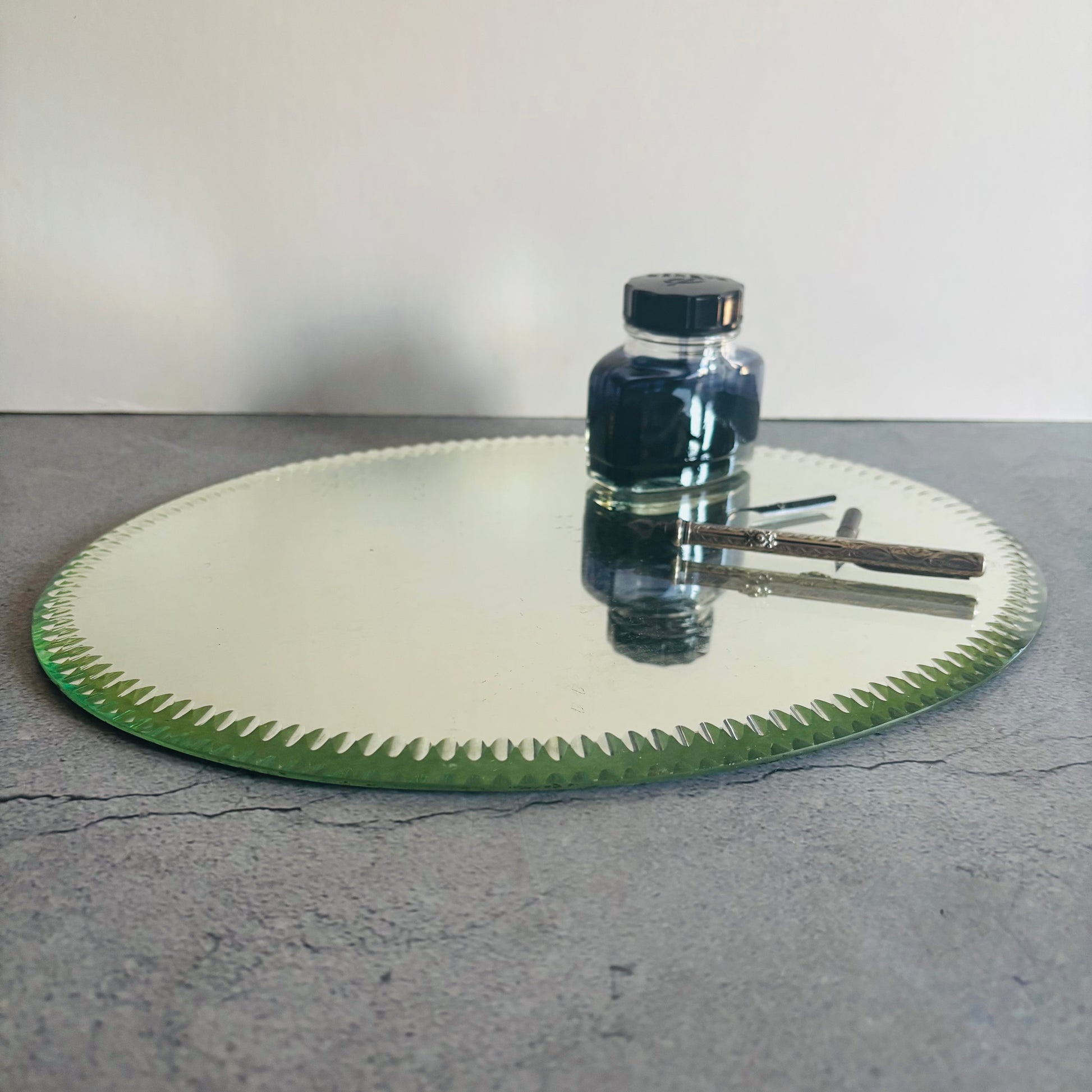 Antique Oval Sorcerers Mirror Mat Gypsy Mirror with a bottle of ink on a grey surface