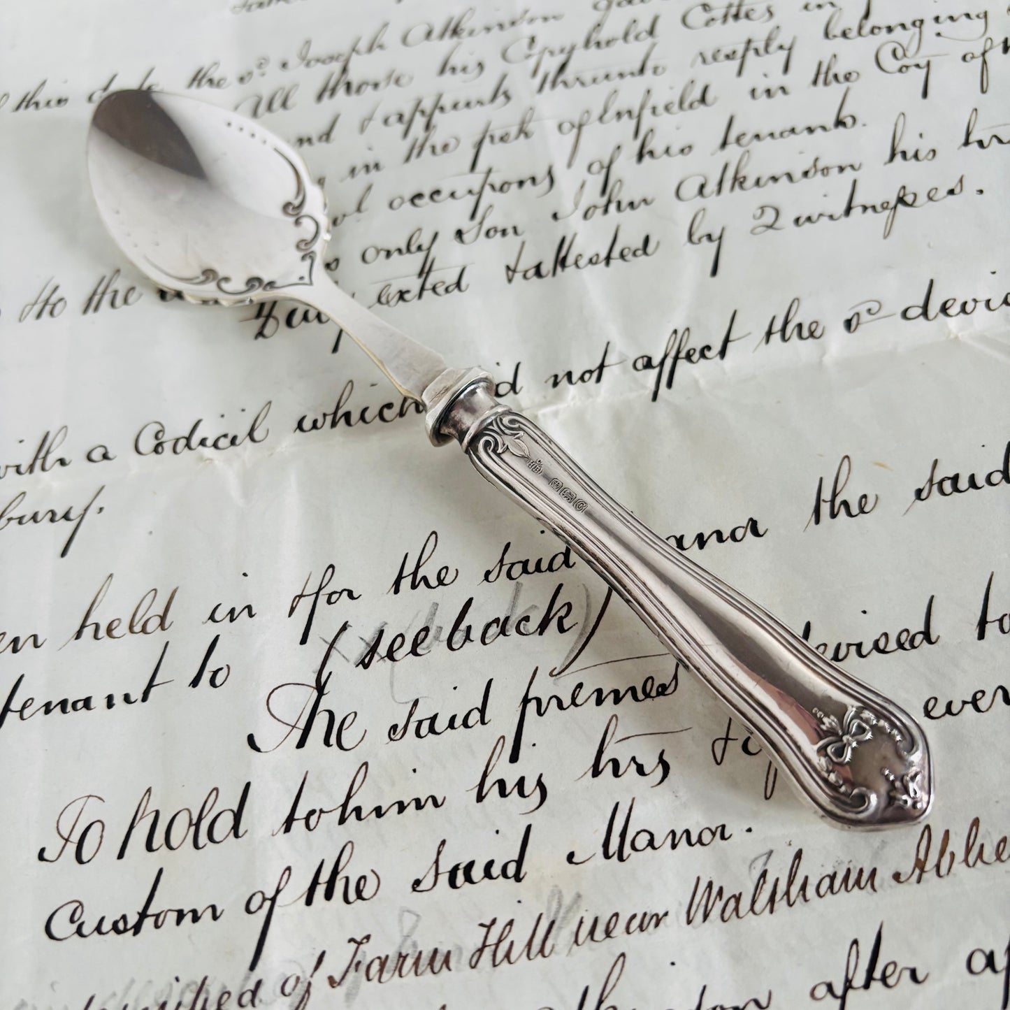 Silver spoon on top of an old document with cursive writing