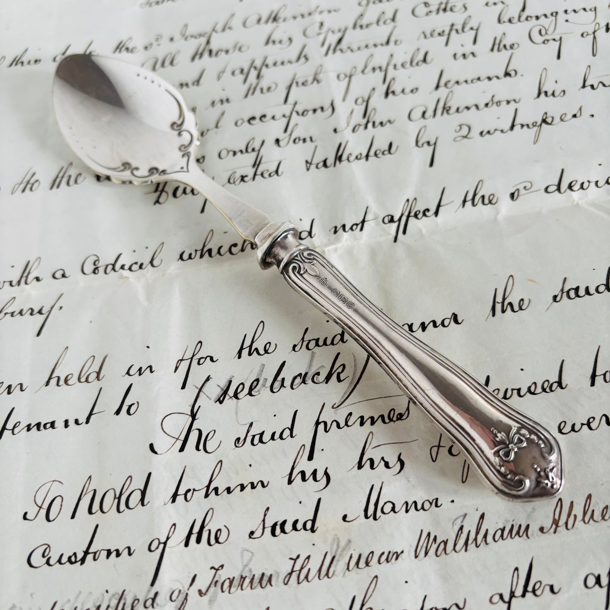 Silver spoon on top of an old document with cursive writing