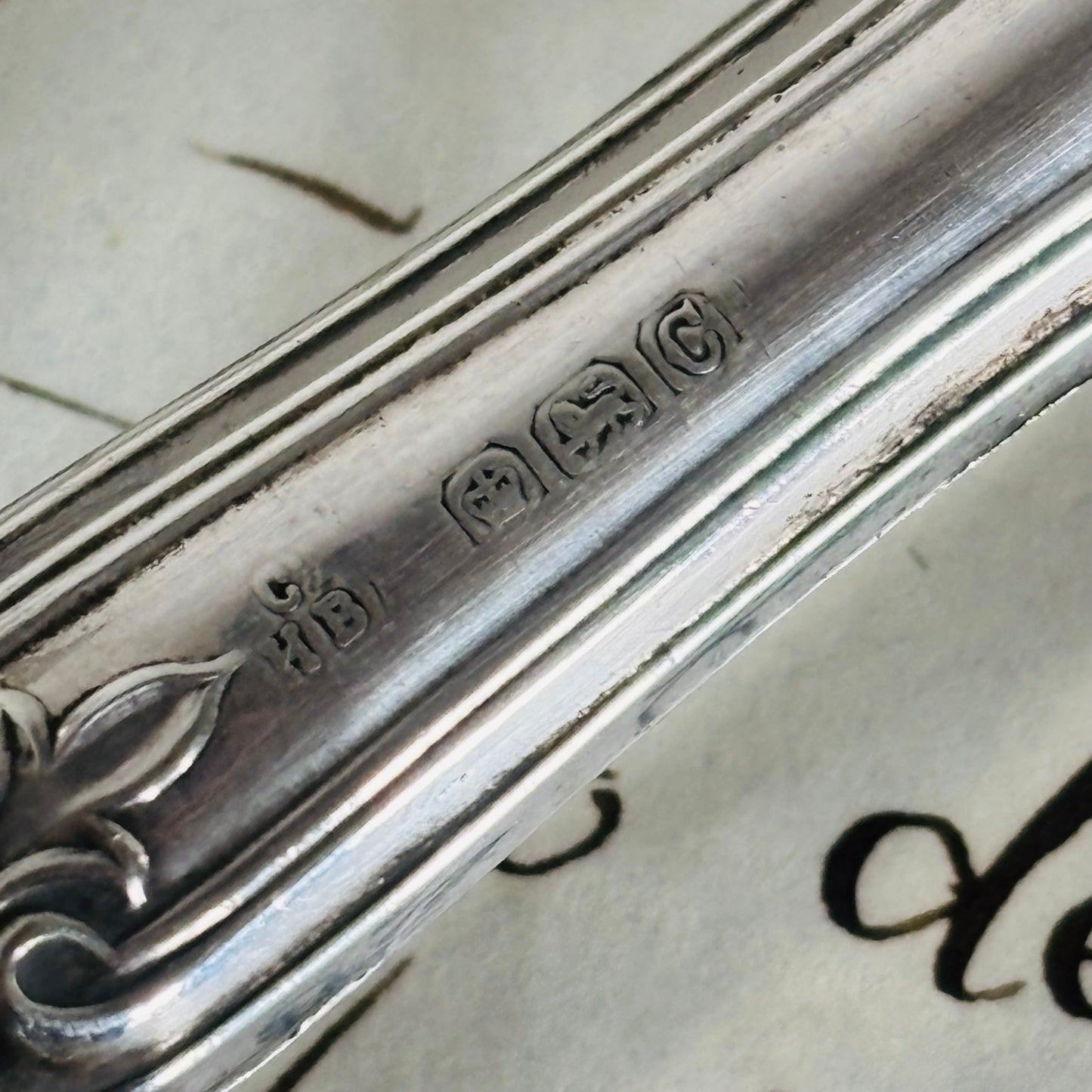 Close-up of a silver spoon with engraved details on a textured surface