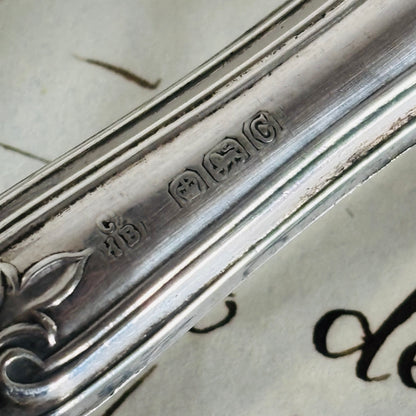 Close-up of a silver spoon with engraved details on a textured surface