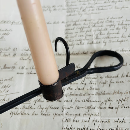 Candle with a metal holder on top of an old document