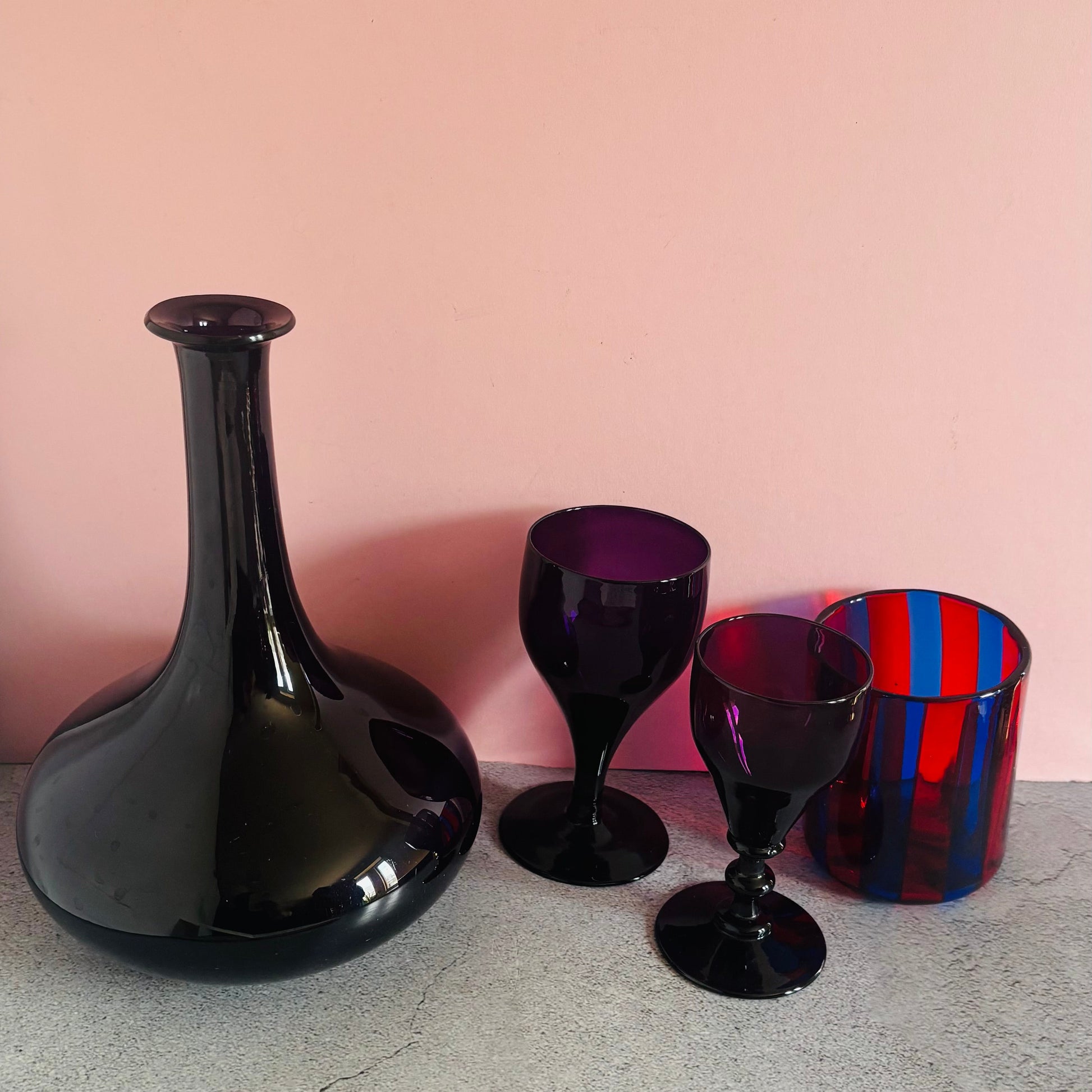 Set of amethyst and multi coloured glassware against a pink background