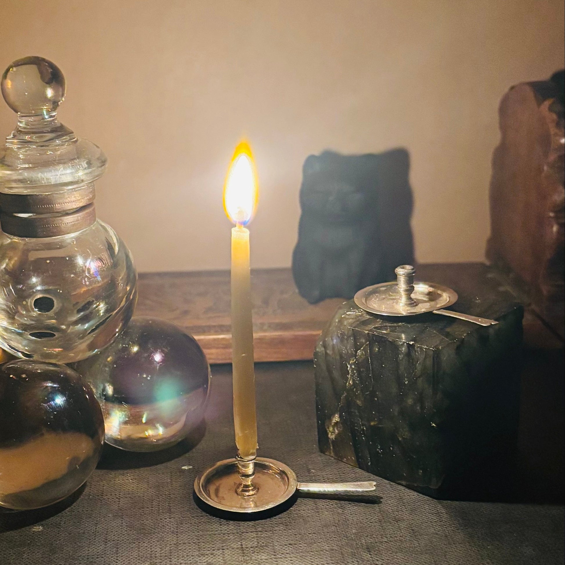 Candlelit scene with glass jars and a stone on a textured surface.