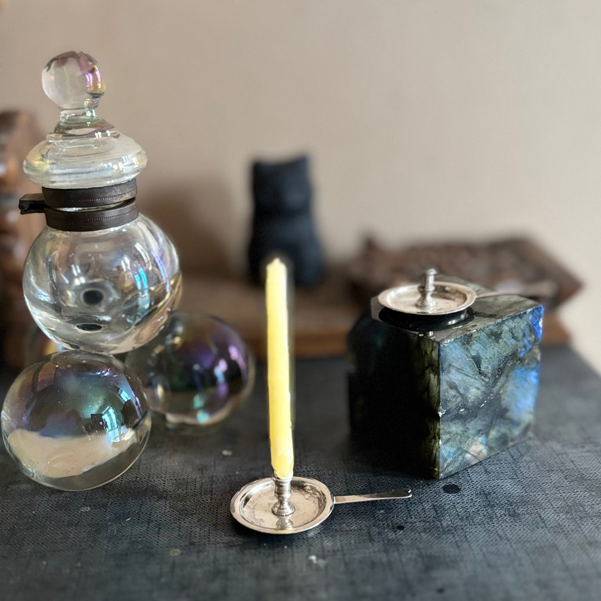Small glass inkwell, a candle on a dark surface with a blurred background