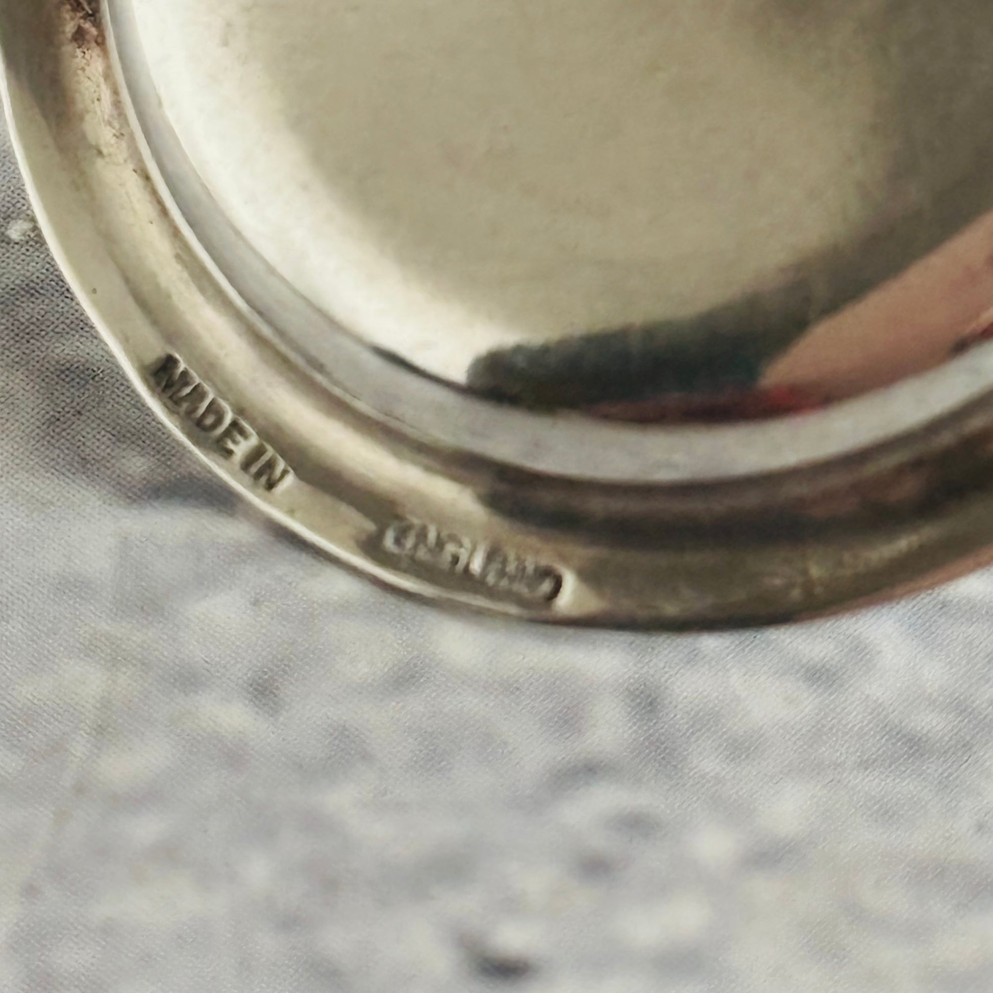 Close-up of a silver object with 'Made in England' engraving on a textured gray background