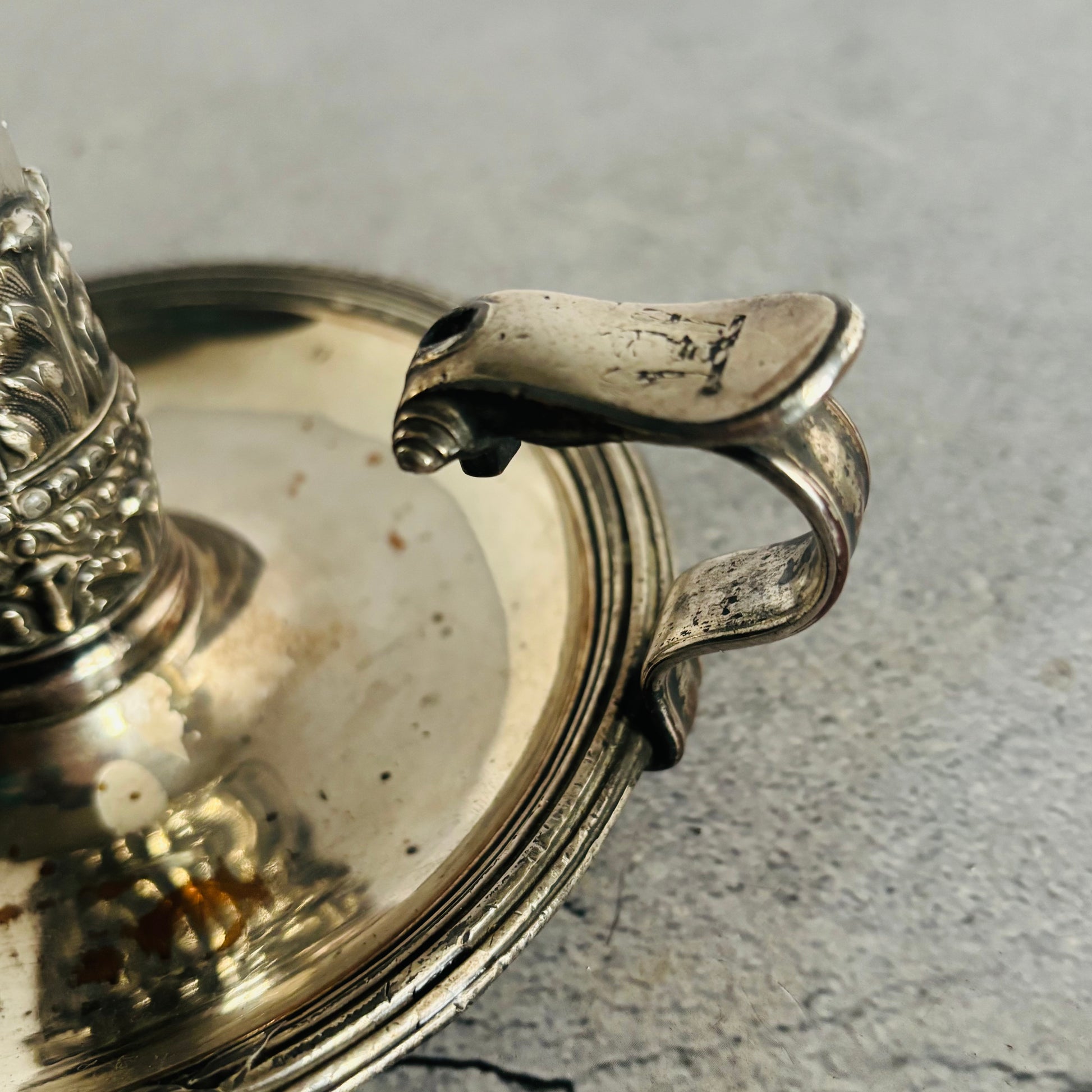 Close-up of a silver decorative item with intricate designs on a grey surface
