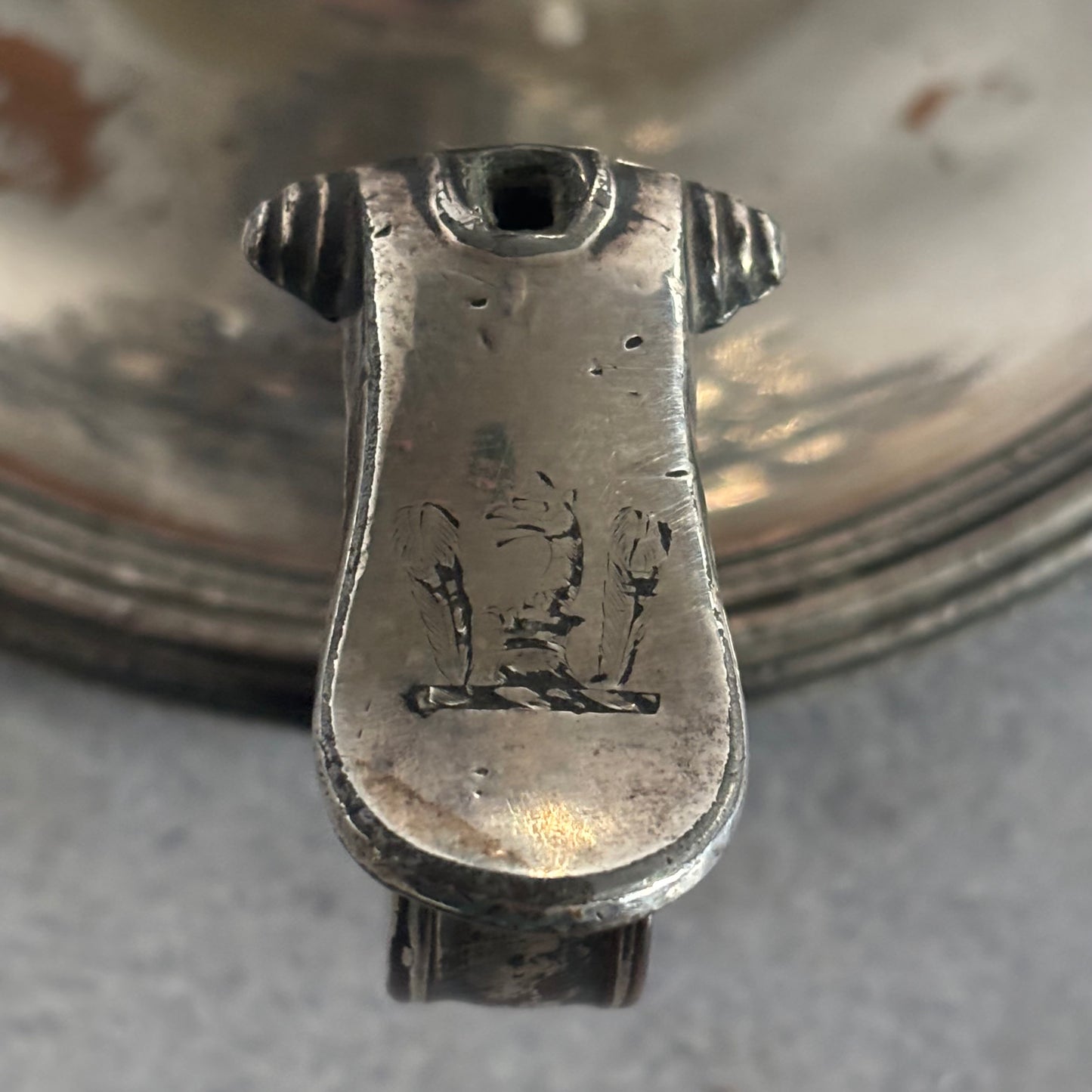 Close-up of a silver object with engraved design on a reflective surface