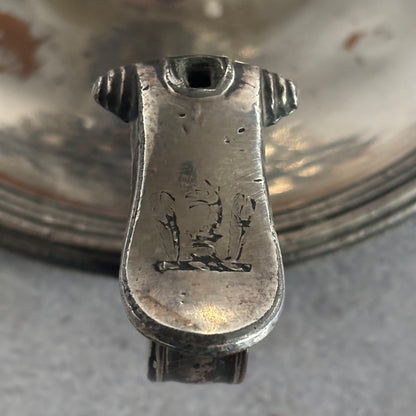 Close-up of a silver object with engraved design on a reflective surface