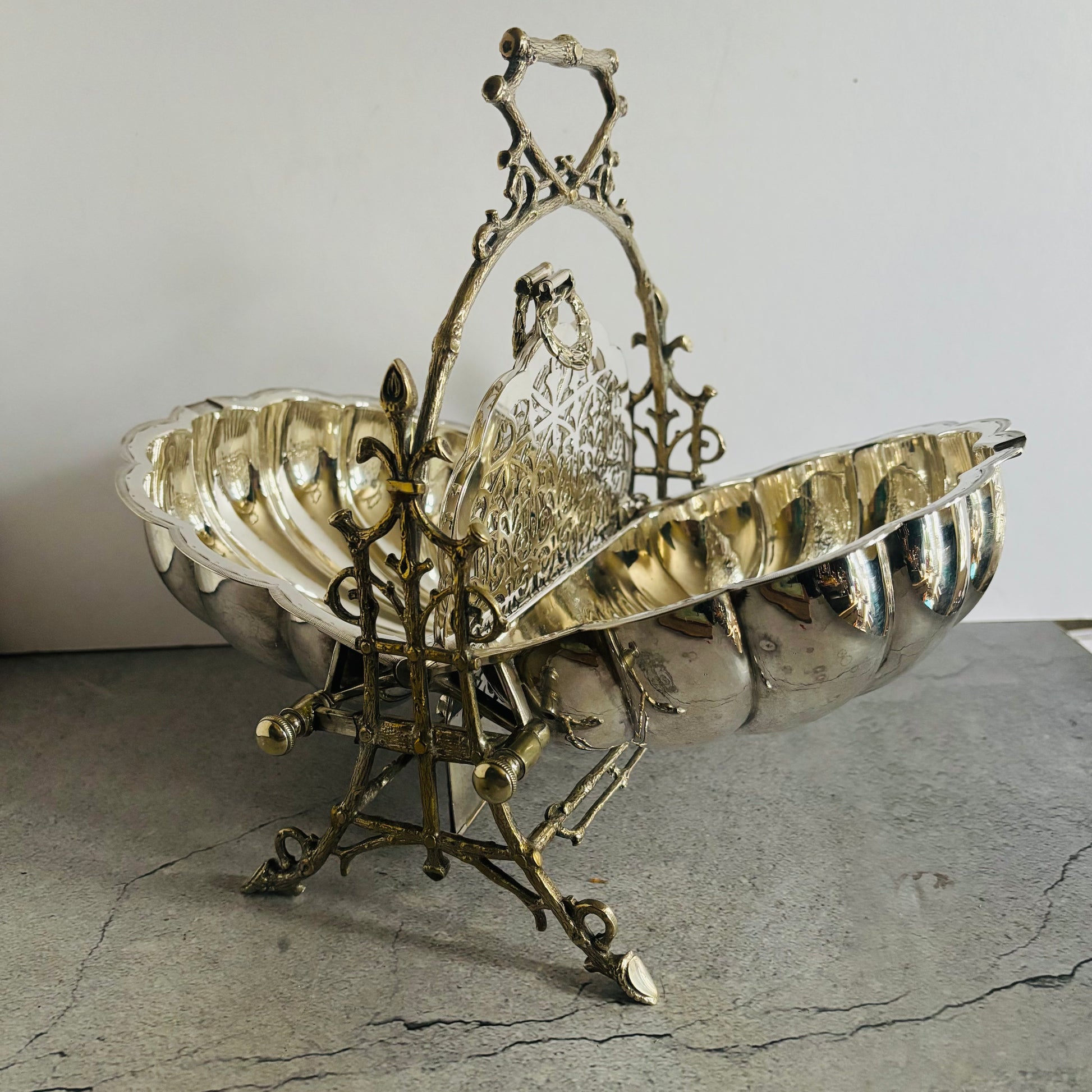 Decorative silver and brass basket on a textured surface with a neutral background