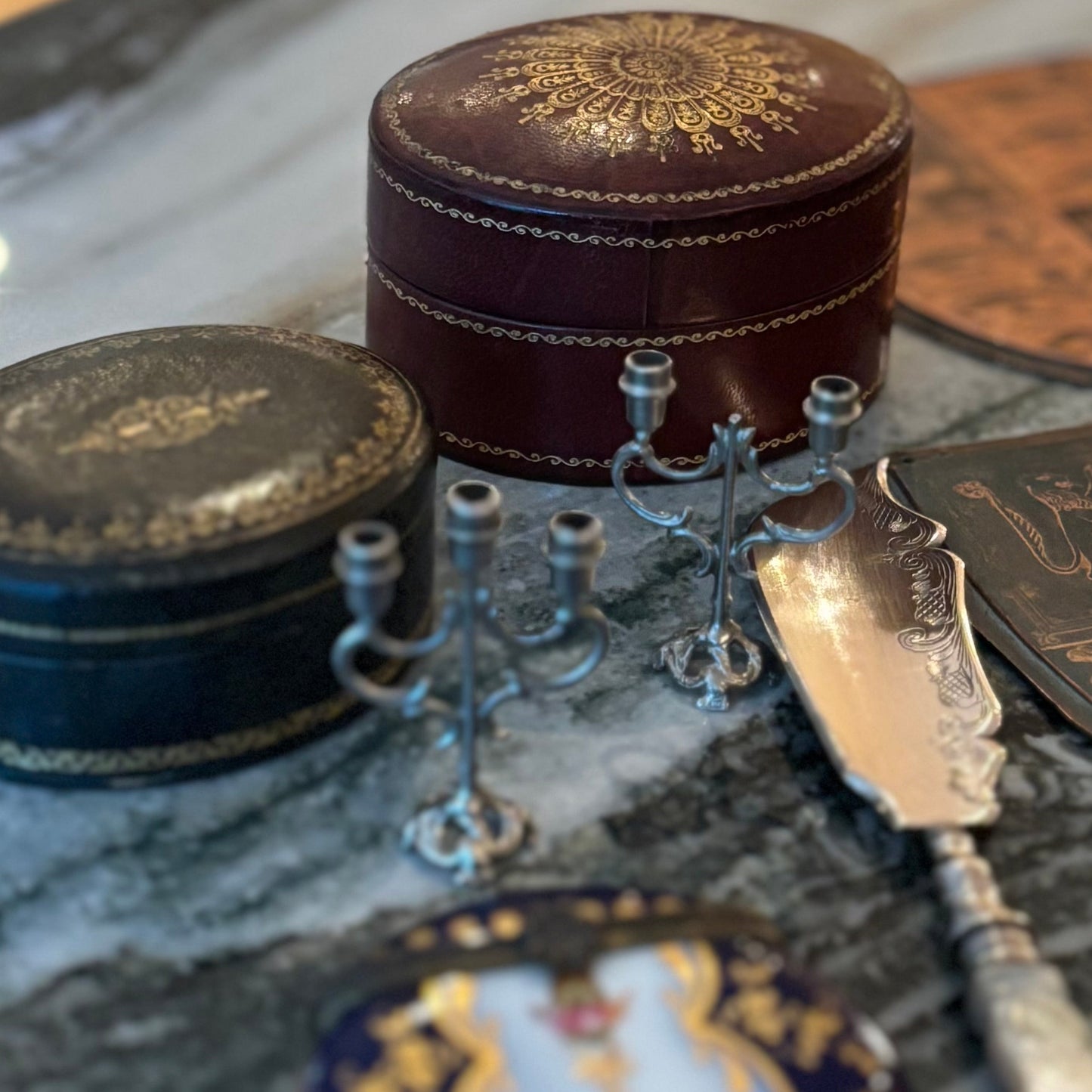 Decorative items including a small round box, a spoon, and a decorative plate on a marble surface.