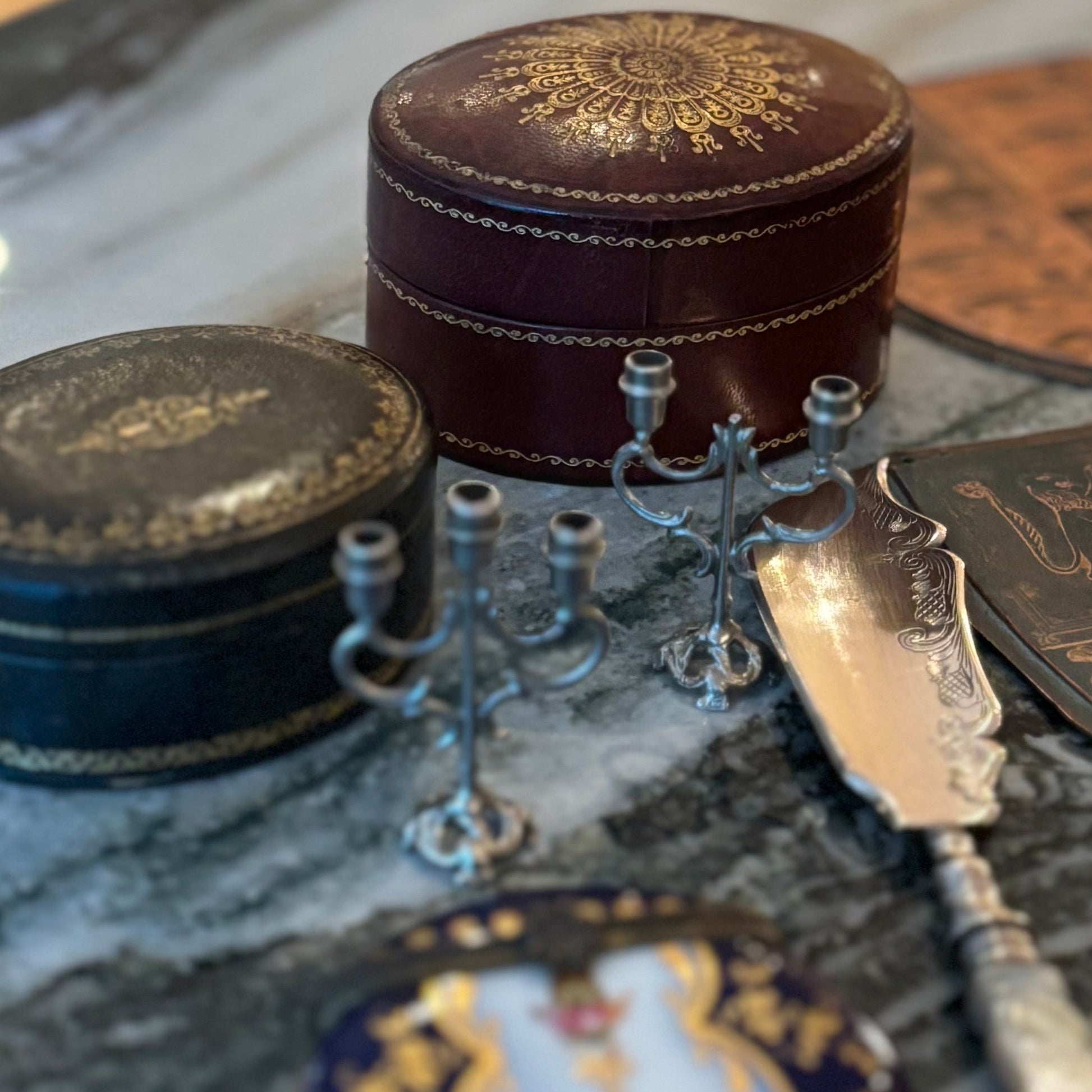 Decorative items including a small round box, a spoon, and a decorative plate on a marble surface.