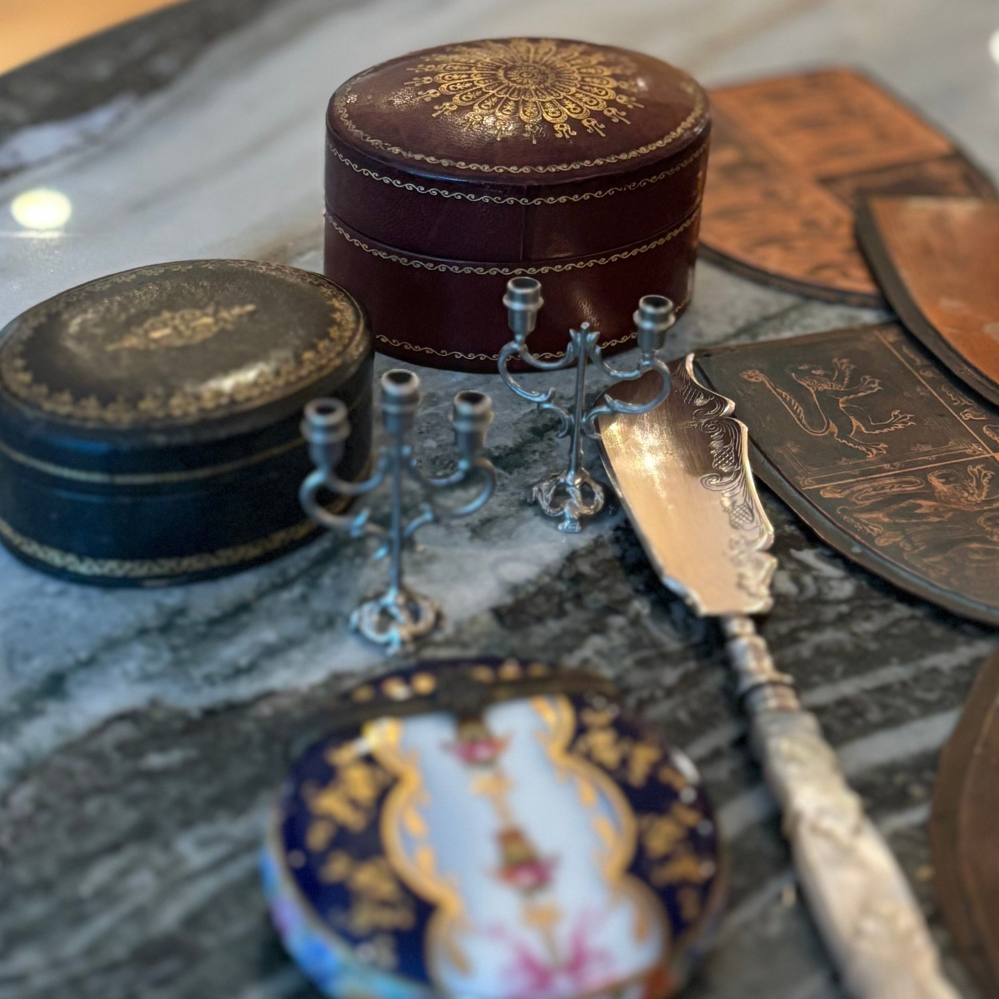 Decorative items including a small round box, a spoon, and a decorative plate on a marble surface.