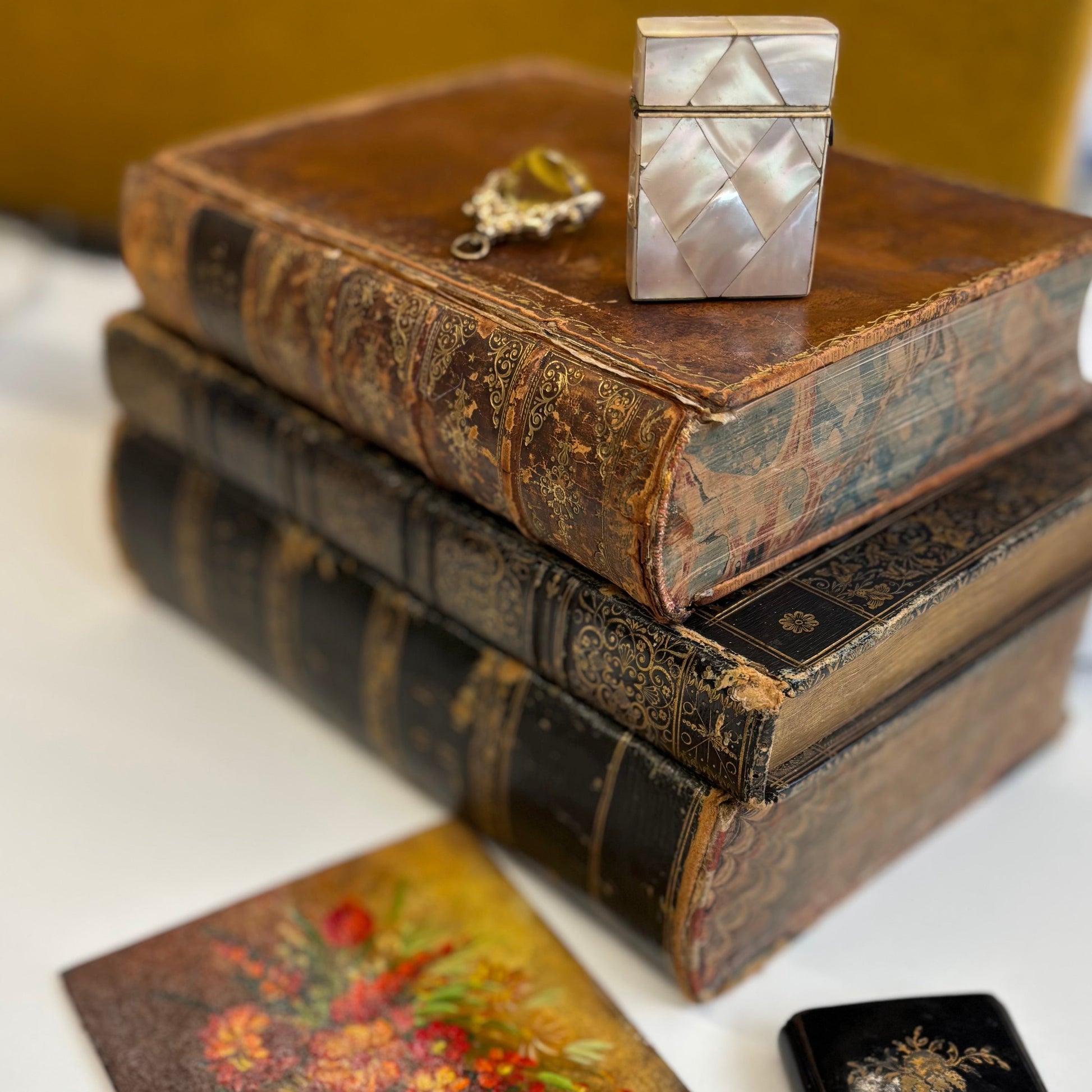 Stack of old books with decorative boxes on a white surface