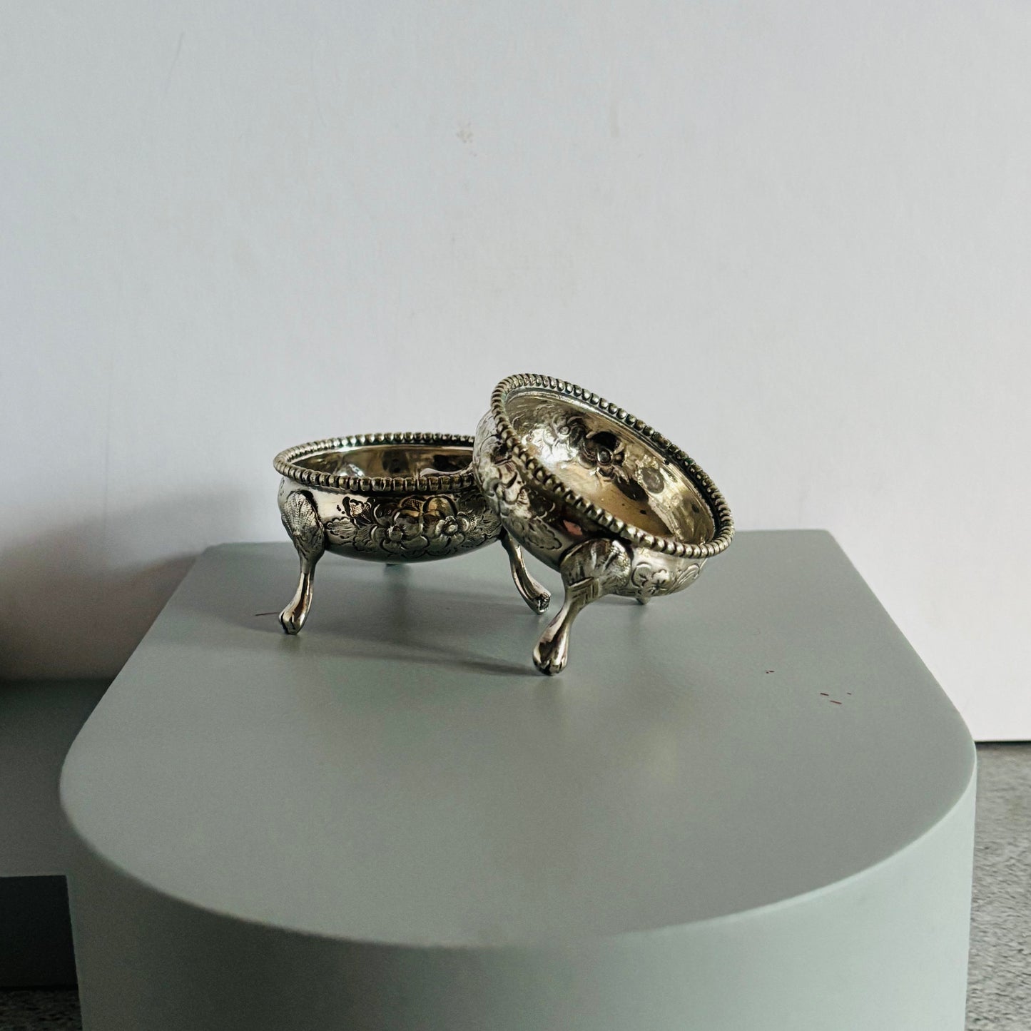 Decorative silver salts on a grey pedestal against white background