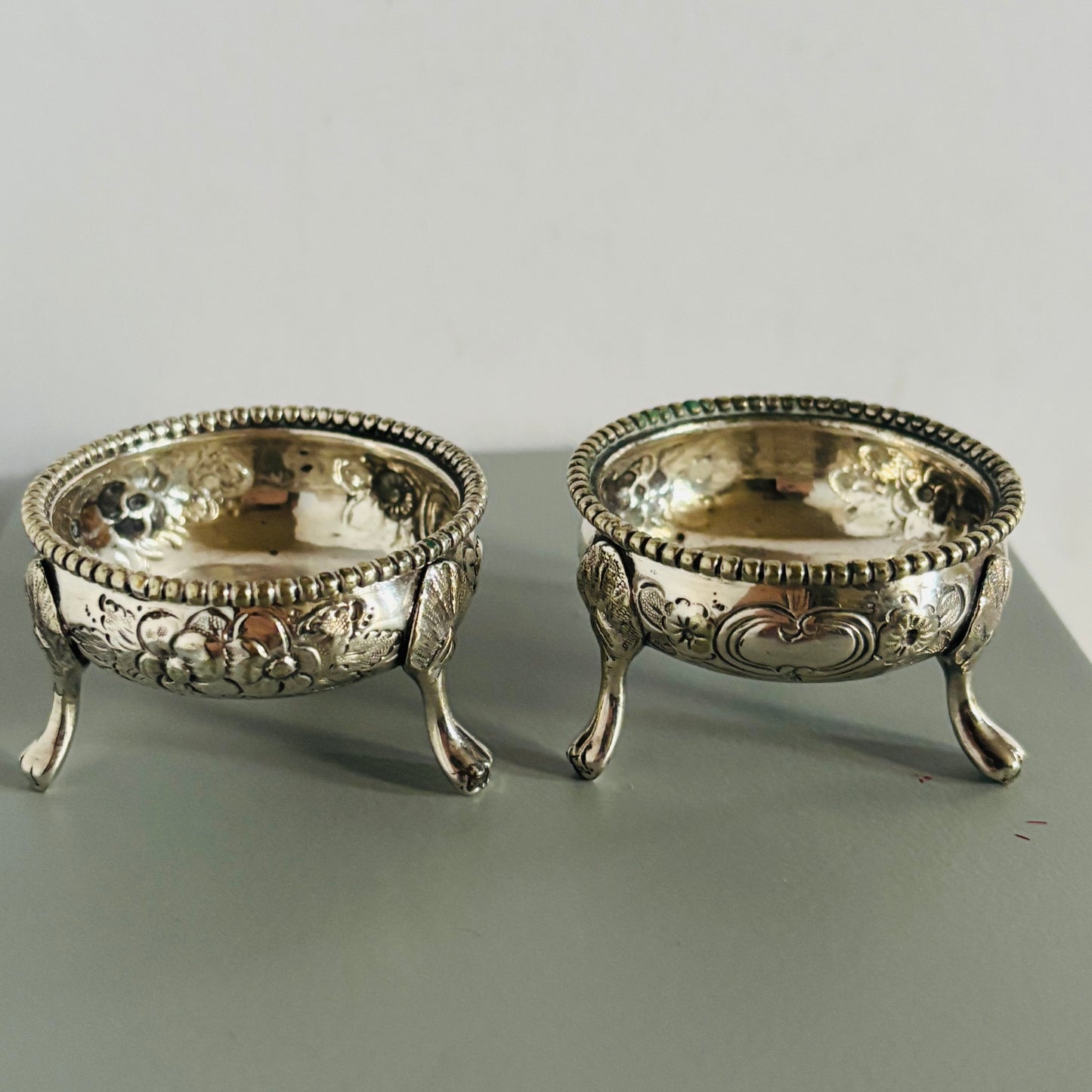Two ornate silver bowls on a gray surface