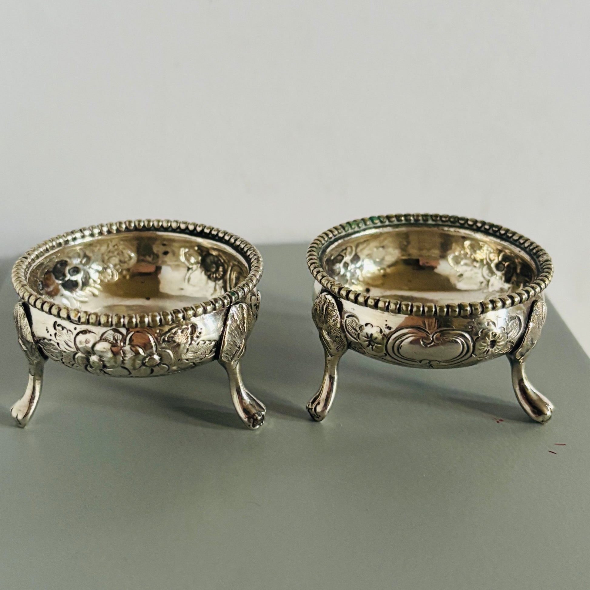 Two ornate silver bowls on a gray surface