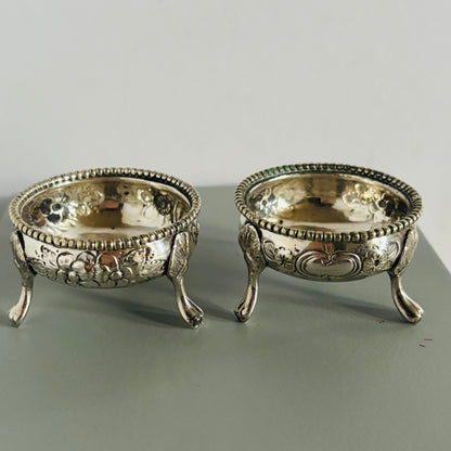Two ornate silver bowls on a gray surface