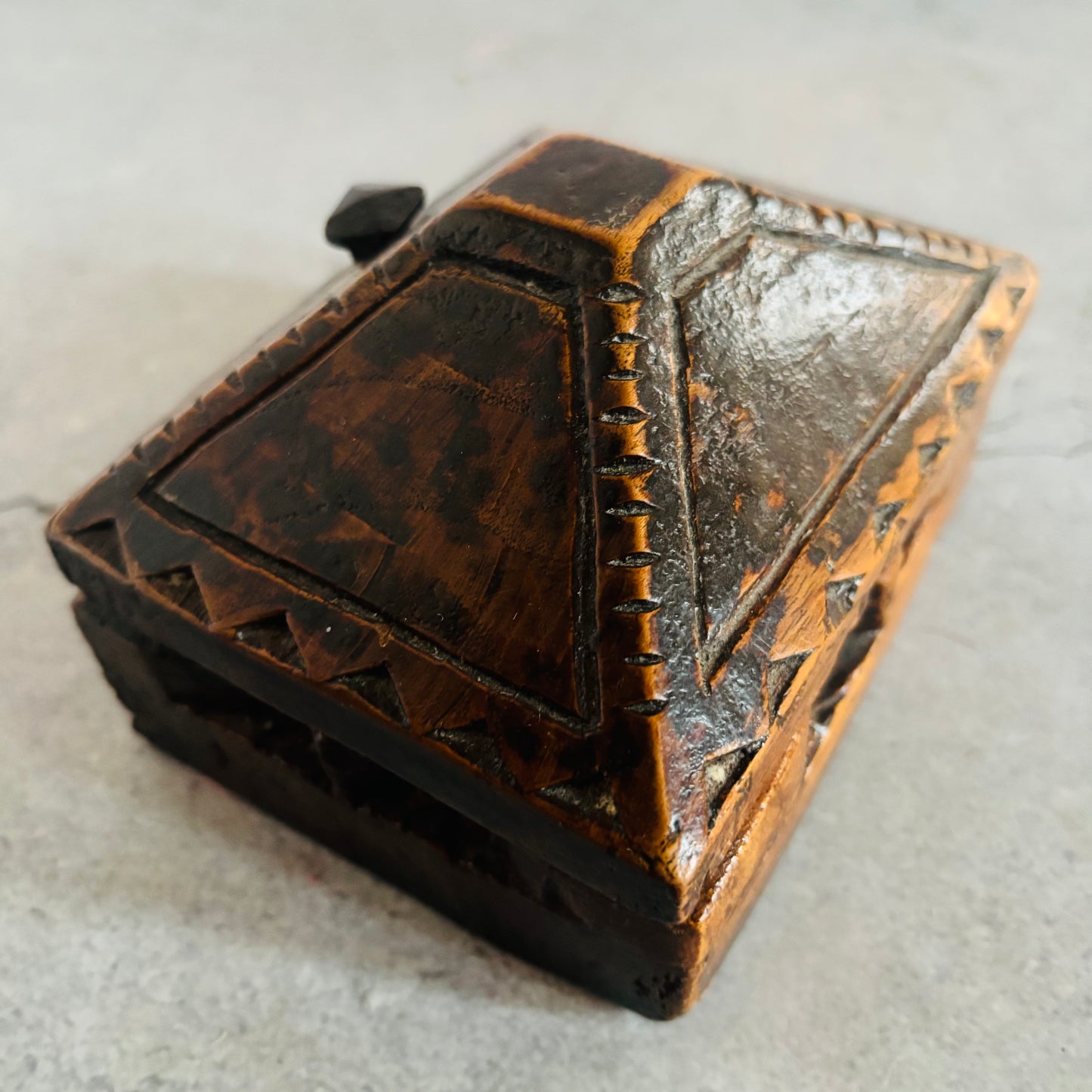 Decorative wooden box with intricate carvings on a light gray background