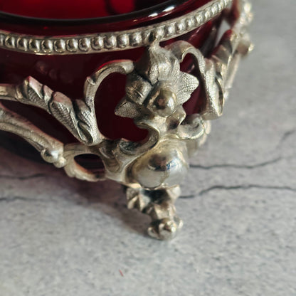 Decorative silver base with intricate designs on a gray surface
