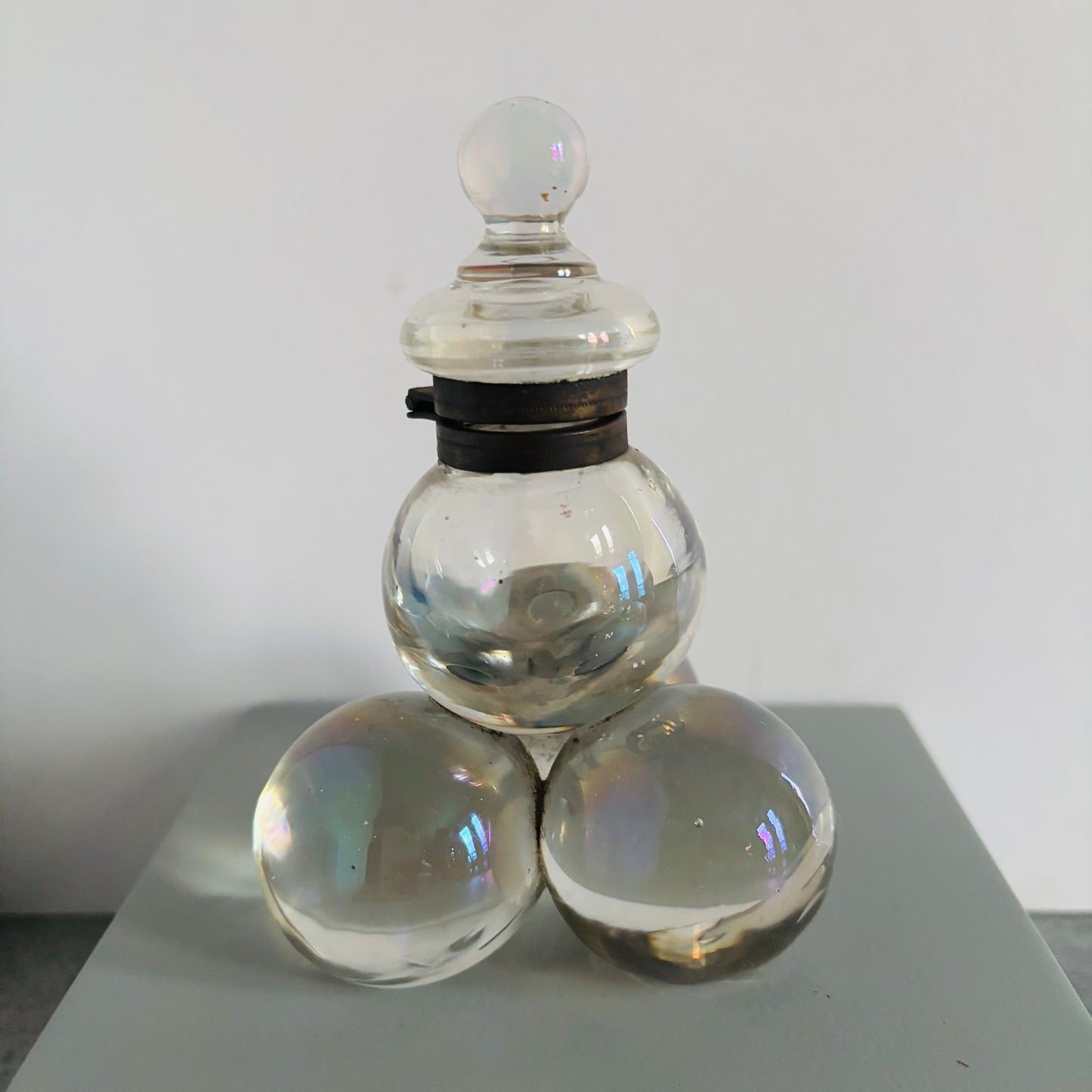 Clear glass container with three spherical elements on a white background