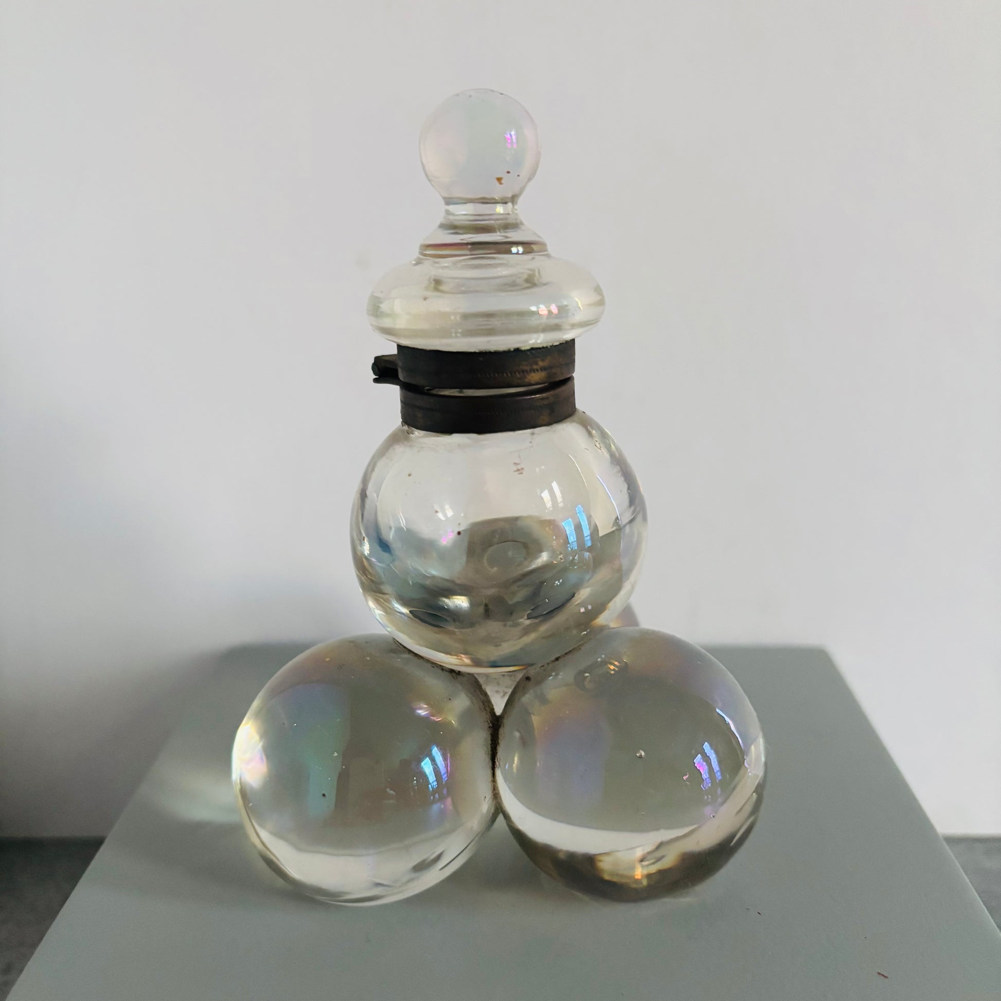Clear glass container with three spherical elements on a white background