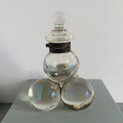 Clear glass container with three spherical elements on a white background