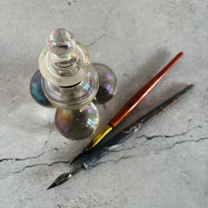 Glass inkwell with a pen on a textured surface