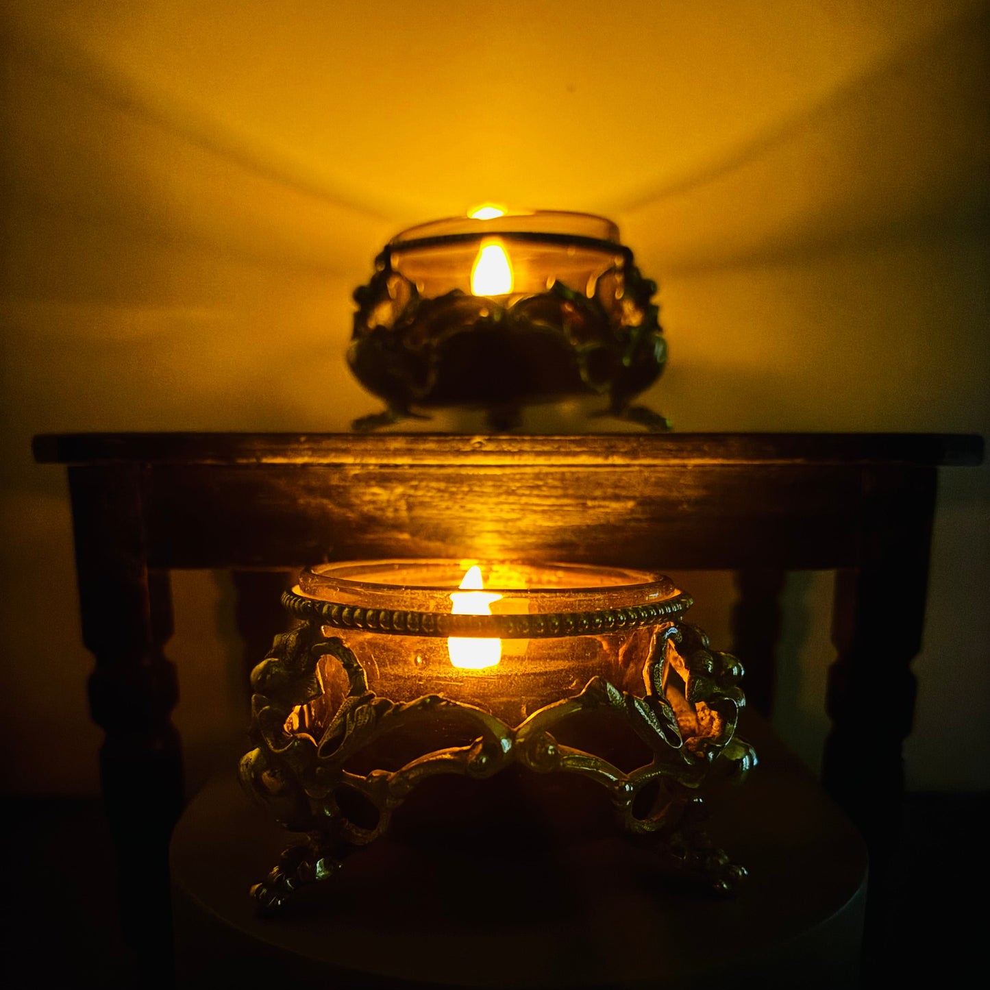 Two lit candles in Ornate Antique Silver Salt cellars with a warm glow