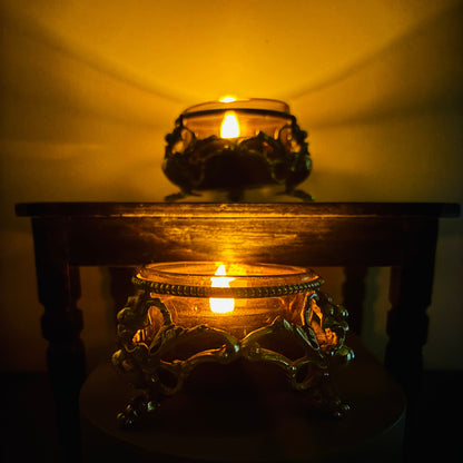 Two lit candles in Ornate Antique Silver Salt cellars with a warm glow