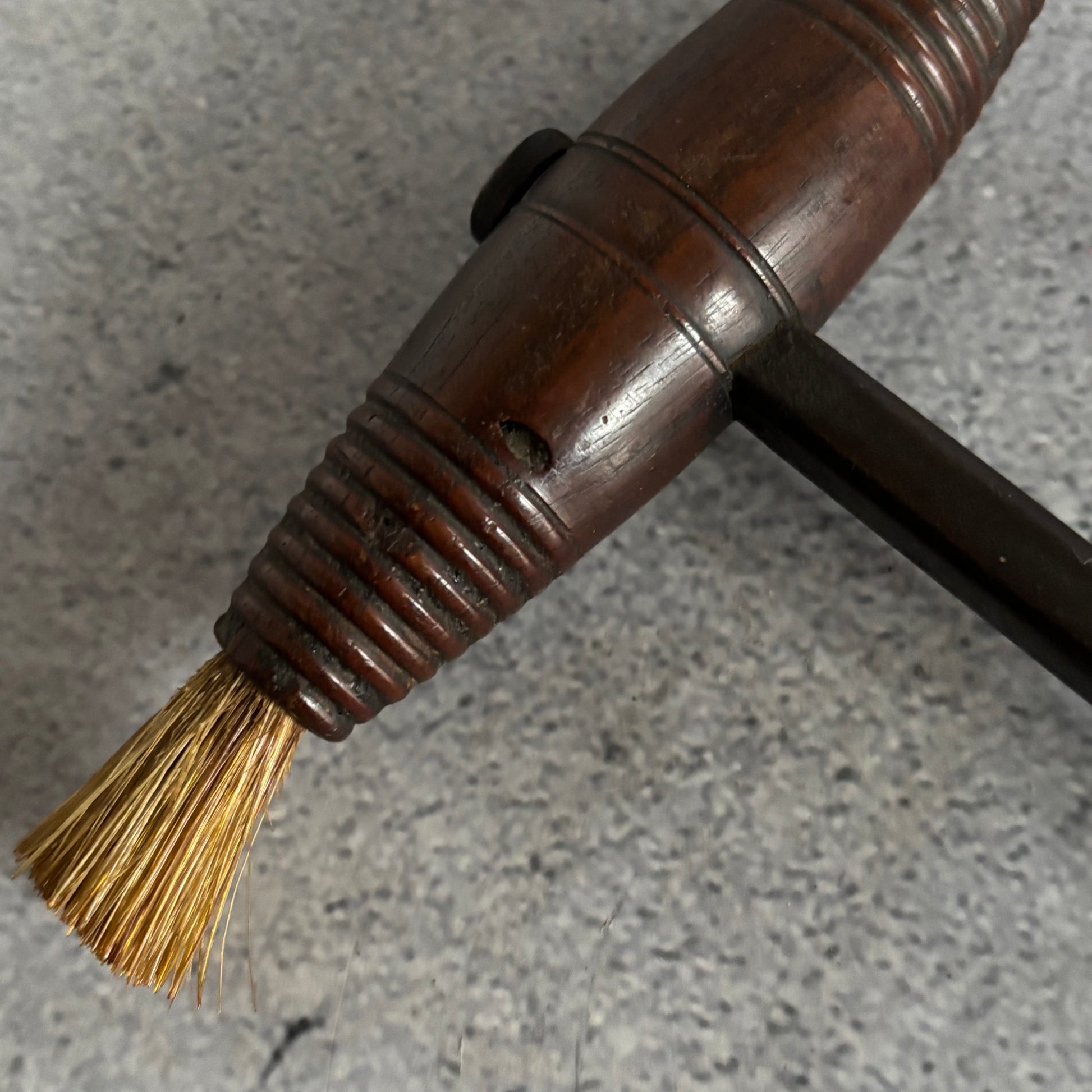 Close-up of a brush with a wooden handle on a gray surface