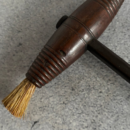 Close-up of a brush with a wooden handle on a gray surface