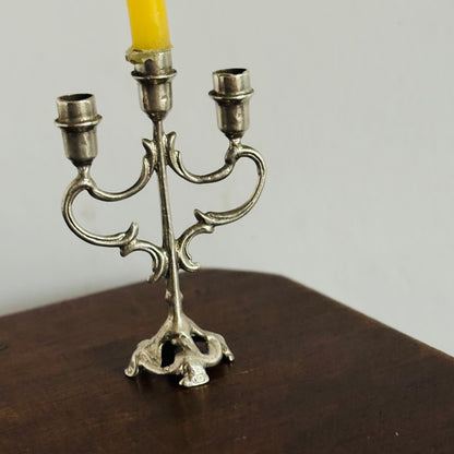 Silver candelabra with a yellow candle on a wooden surface and light gray background