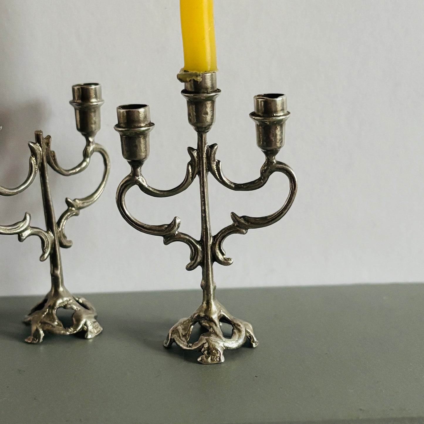 Silver candelabra with a yellow candle on a gray surface and background