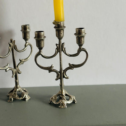 Silver candelabra with a yellow candle on a gray surface and background