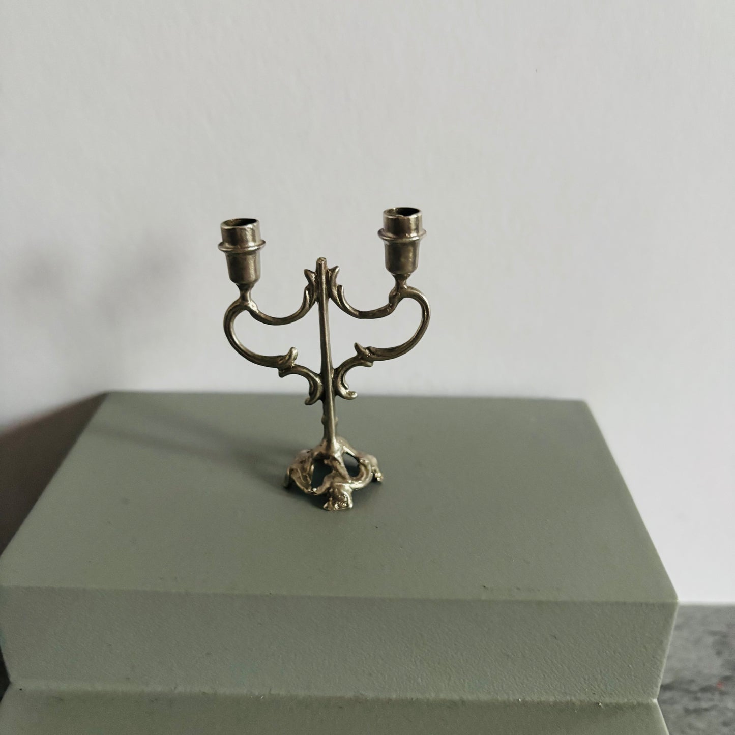 Small ornate metal candle holder on a gray surface with a neutral background