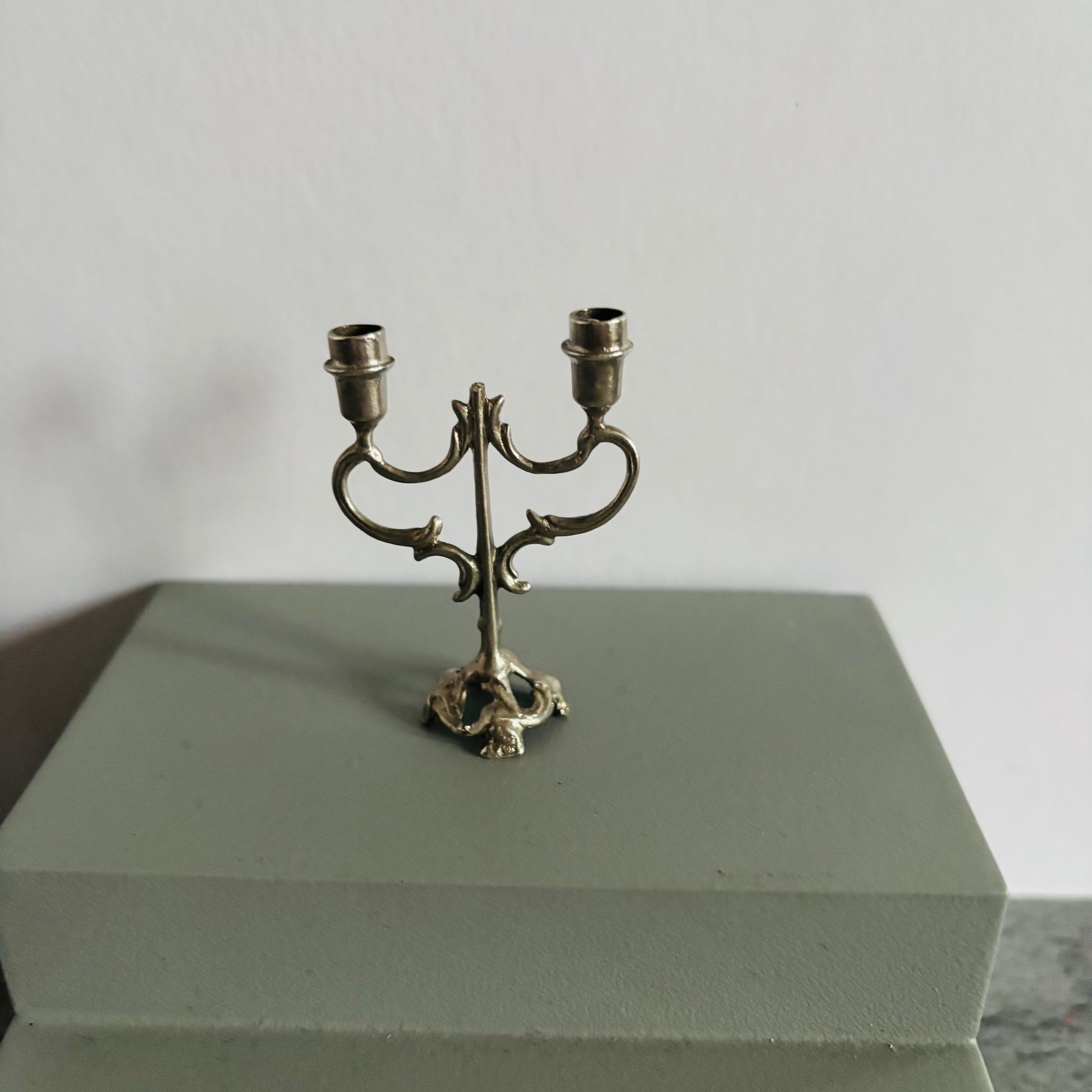 Small ornate metal candle holder on a gray surface with a neutral background