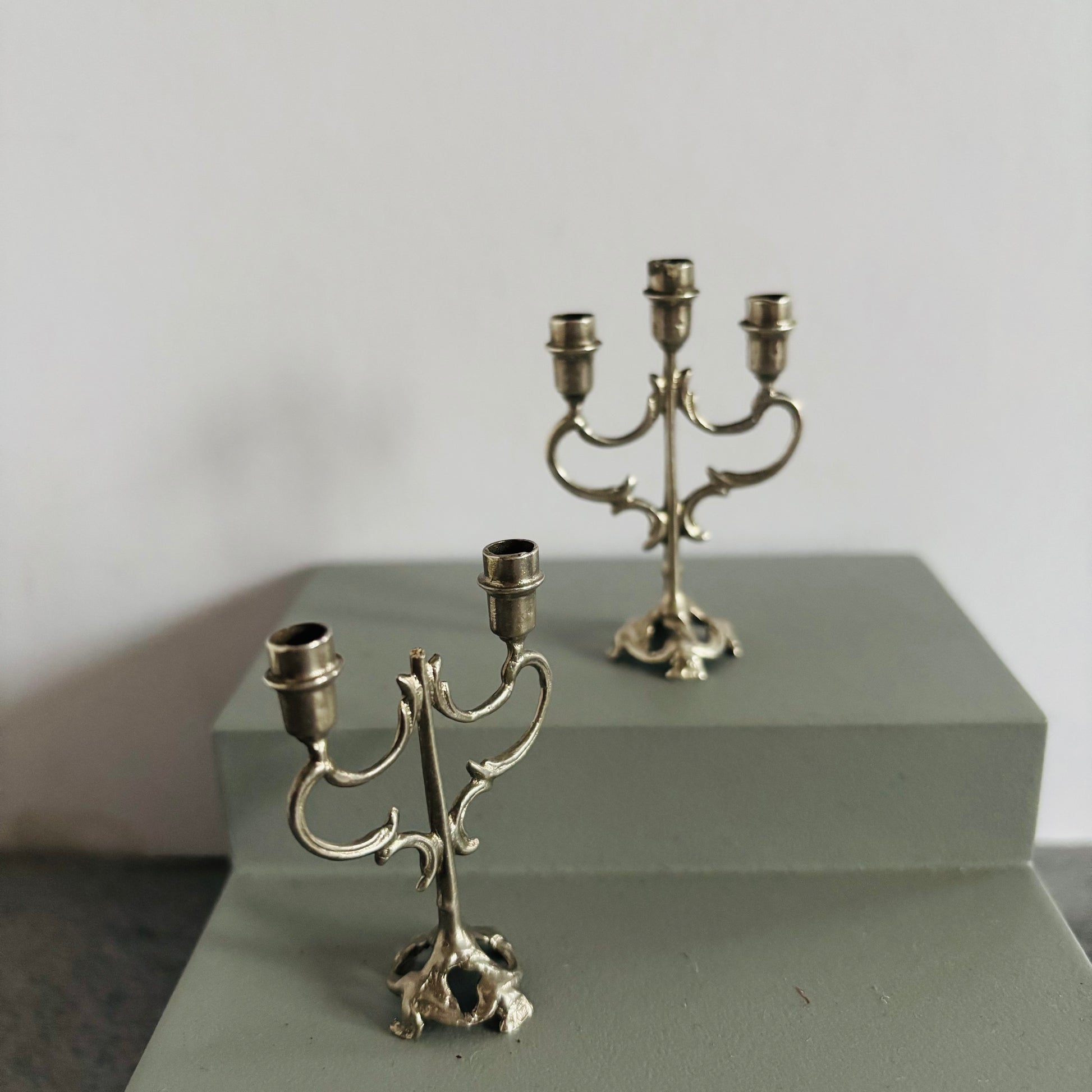 Two silver candelabras on a gray surface with a plain background