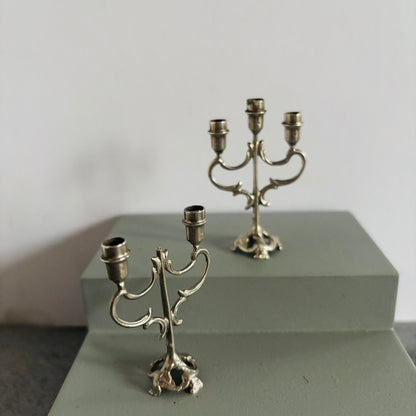 Two silver candelabras on a gray surface with a plain background